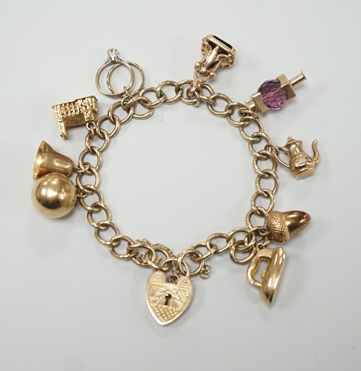 A 9ct gold oval link charm bracelet, hung with ten assorted charms including nine 9ct gold, gross weight 31.9 grams.